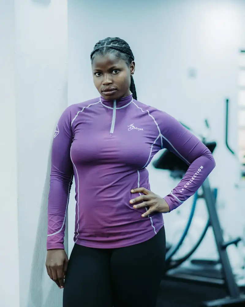 Member in a purple training top standing confidently by the equipment