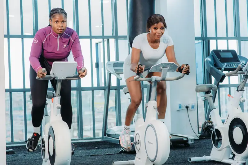 Two Savfol members riding exercise bikes side by side in a cardio class