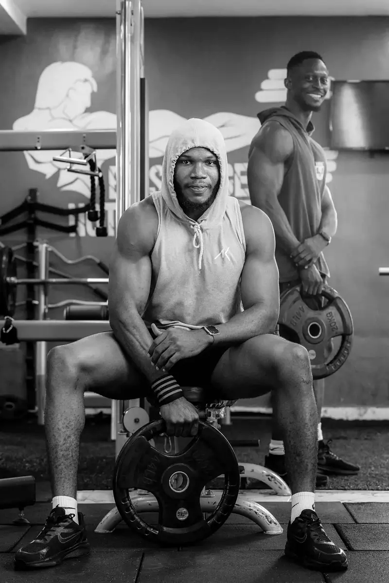 Two Savfol members resting between sets beside a rack of weight plates